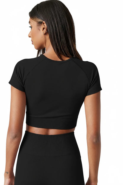 Person wearing a black crop top and skirt set against a neutral background
