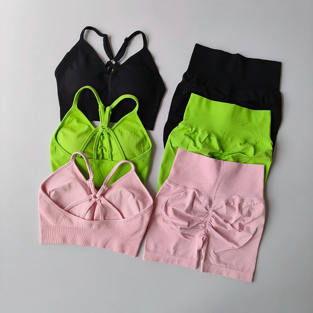 Set of black, green, and pink sports bras and shorts