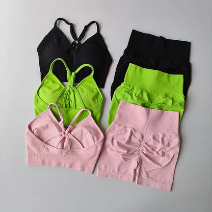 Set of black, green, and pink sports bras and shorts