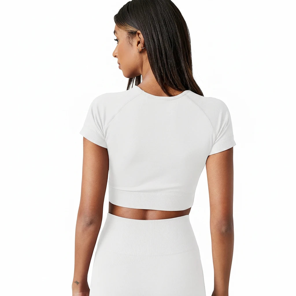 Person wearing a white crop top and pants on a plain background