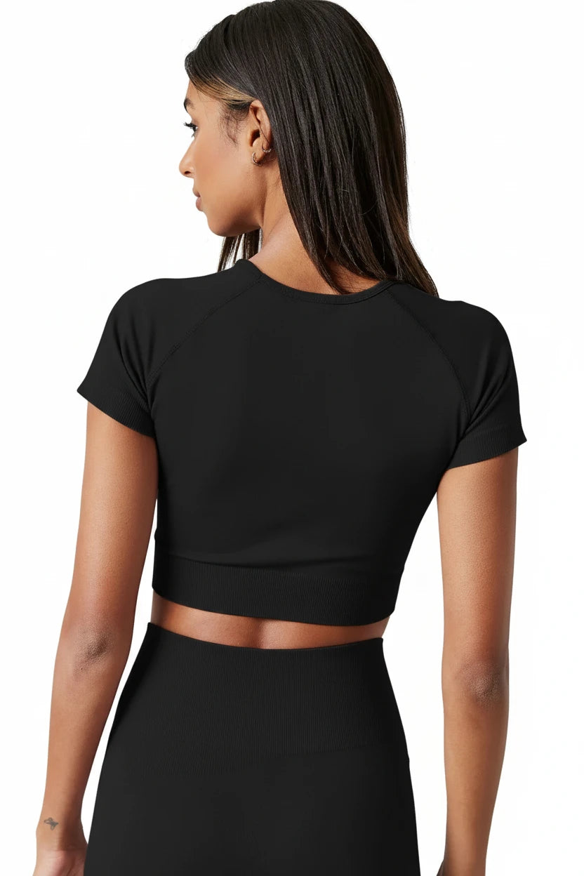 Person wearing a black crop top and skirt set against a neutral background