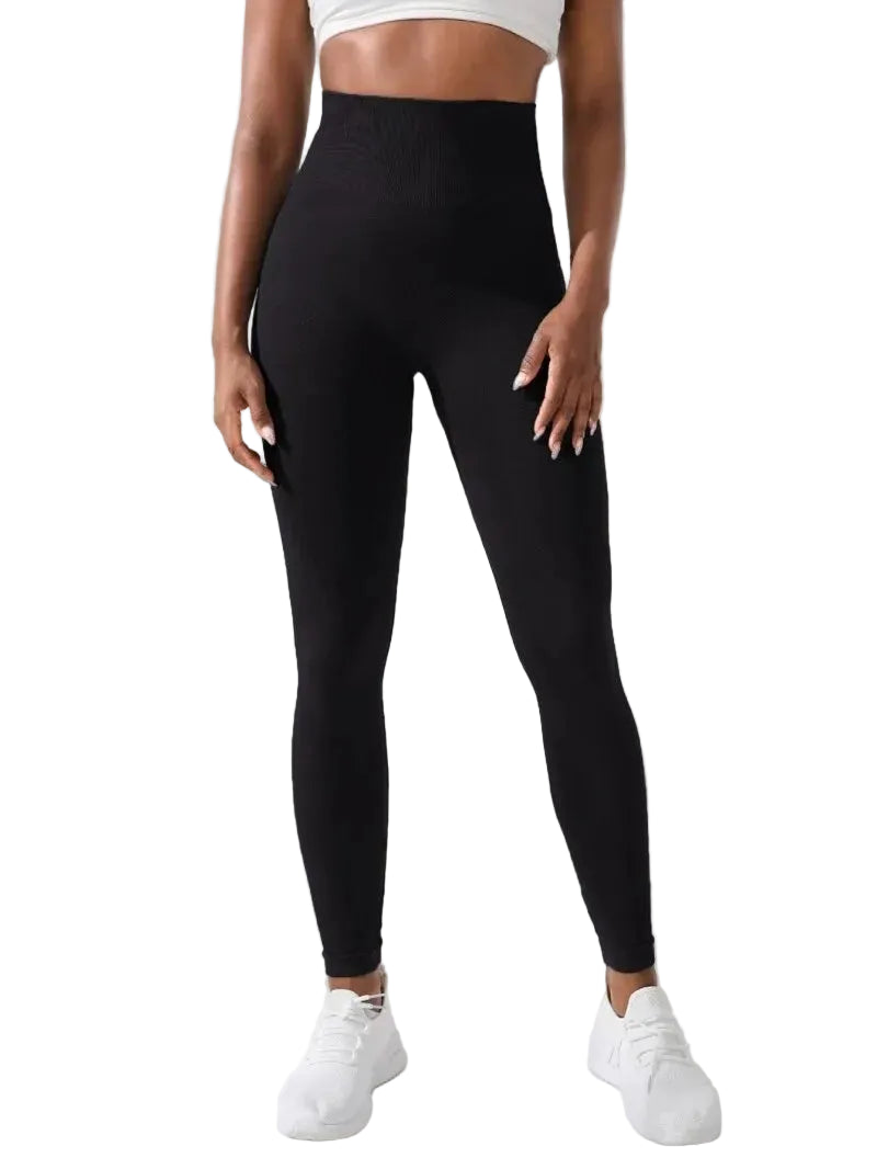 Person wearing black leggings and white sneakers against a white curtain background