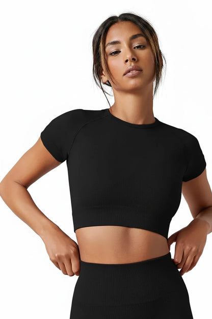 Woman wearing a black crop top against a plain background