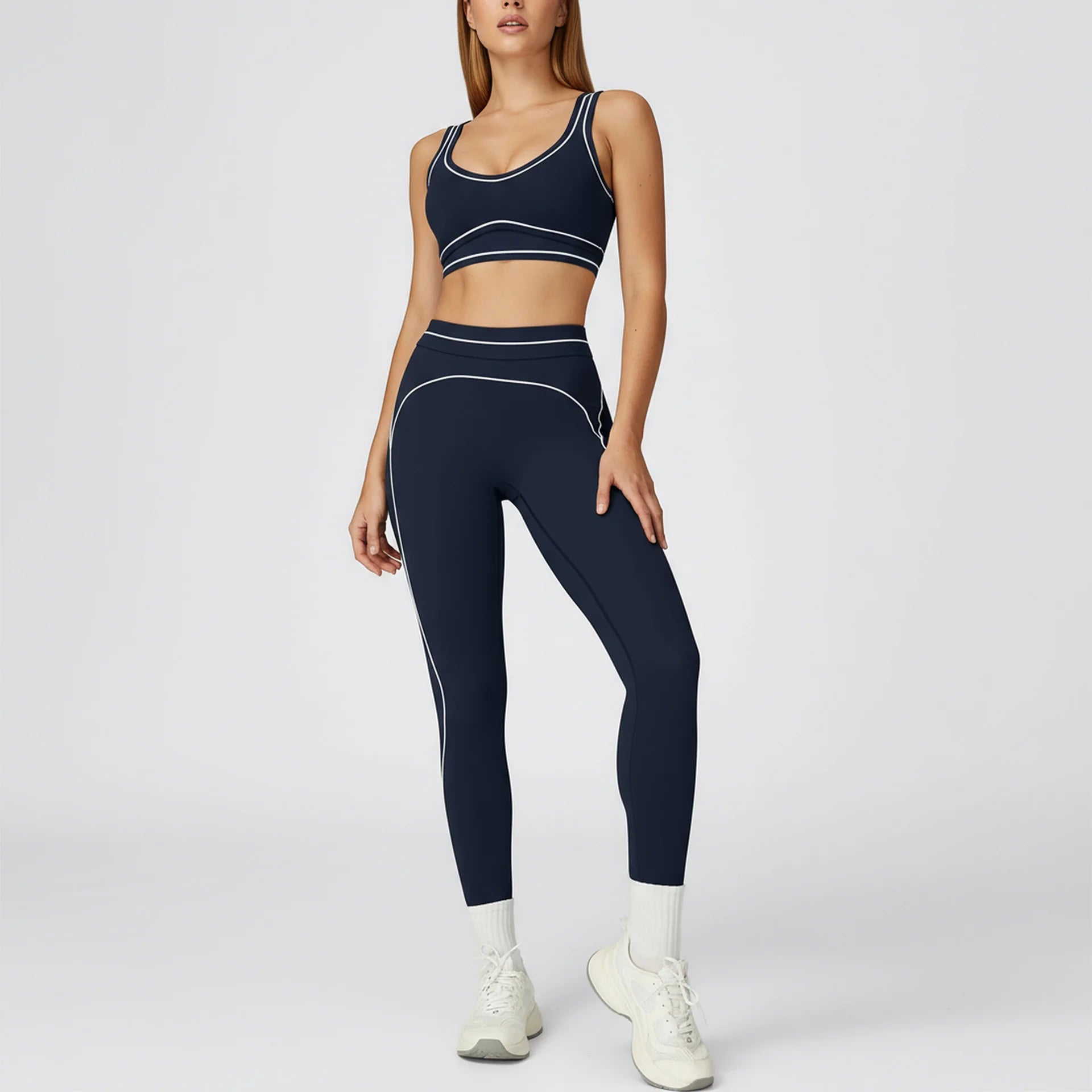 Woman wearing a navy sports bra and leggings set on a white background