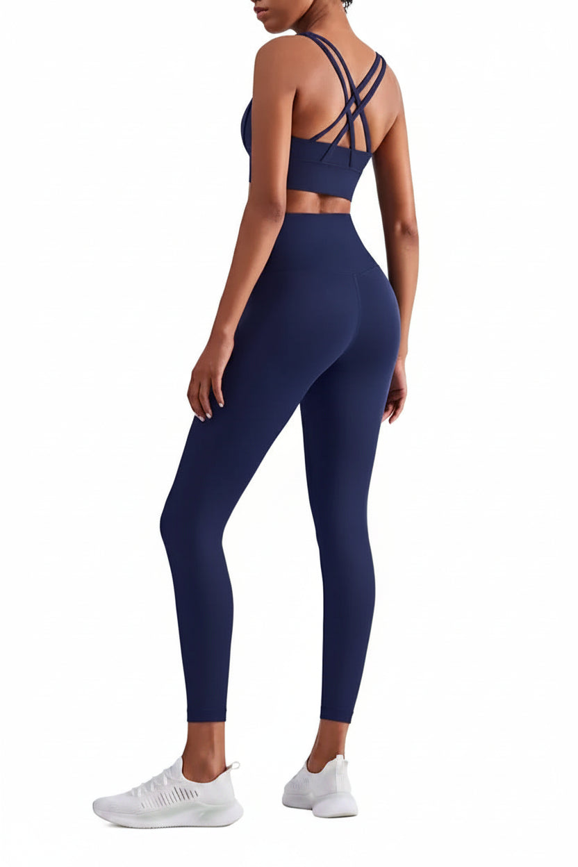 Person wearing a navy blue sports bra and leggings set on a white background